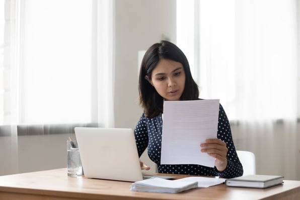 Someone working at a laptop looking at a document