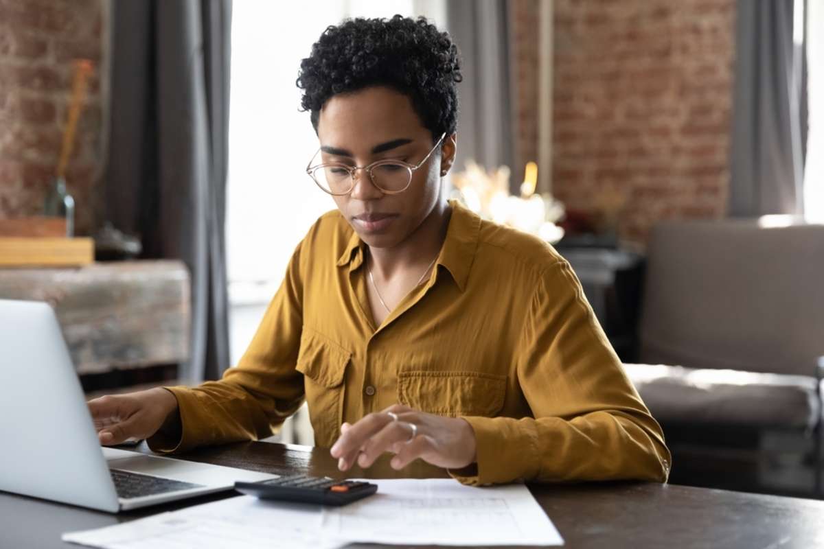 Woman working at a computer with a calculator, accounting and property management services concept